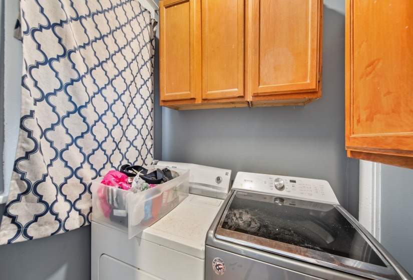 Laundry area featuring wood cabinetry, painted walls, and window with patterned coverings