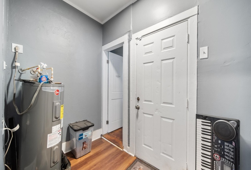 Interior utility area featuring a water heater, wood-finish flooring, and two paneled interior doors
