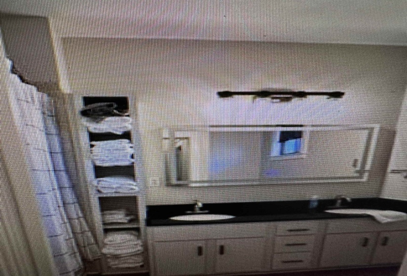 Dual vanity with integrated sinks, dark countertop, and light-toned cabinetry