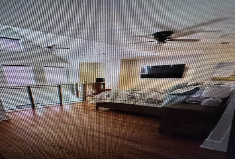 Loft sleeping area featuring sloped ceilings, two ceiling fans, wood-finish flooring, and a metal-railed half-wall overlooking the space below