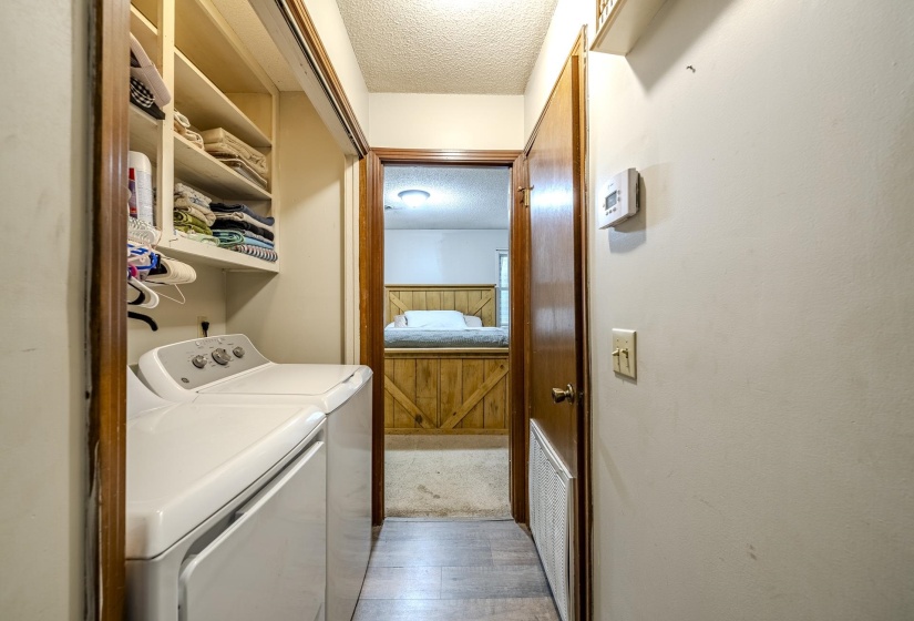 Dedicated laundry area featuring built-in shelving, a white washer and dryer set, and wood-finish door frames