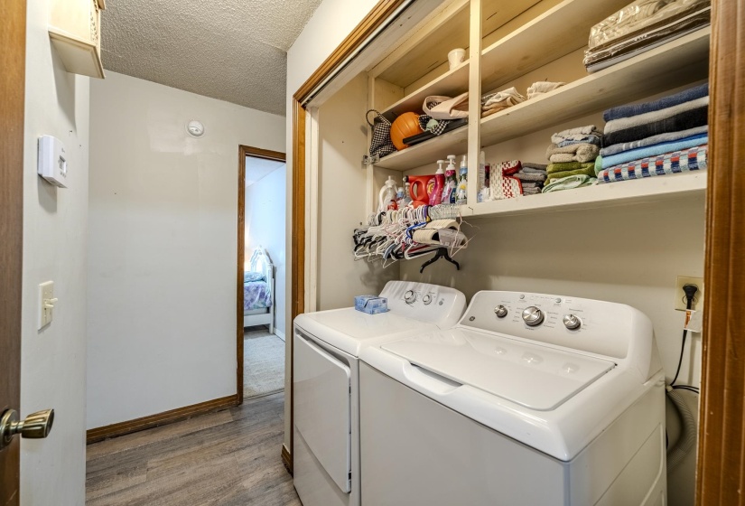 Dedicated laundry area featuring wood-finish flooring, white walls, and a built-in shelving unit