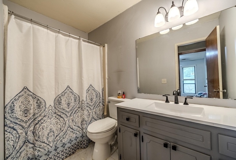 Bathroom vanity featuring a white countertop, an integrated rectangular sink, and matte black hardware