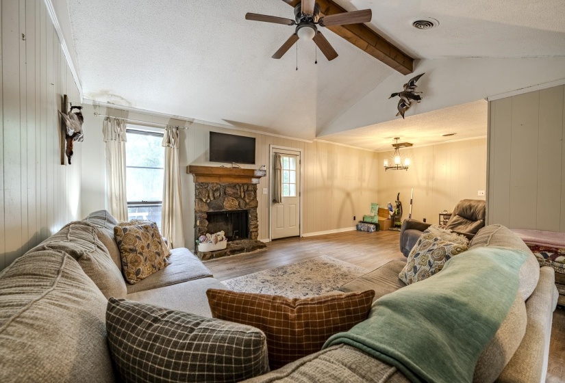 Living area featuring a vaulted ceiling with exposed wood beams, a ceiling fan, and wood-finish flooring