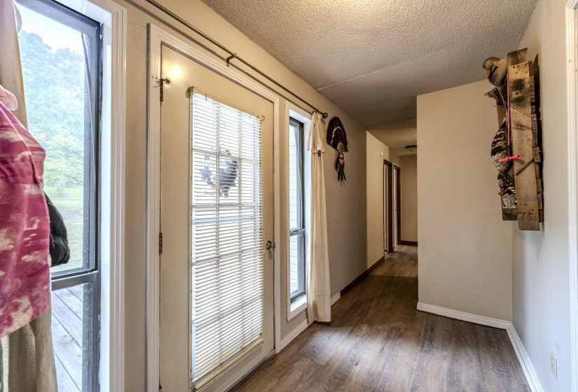 Entryway featuring a glass-paned door with blinds, an adjacent vertical window, and wood-finish flooring