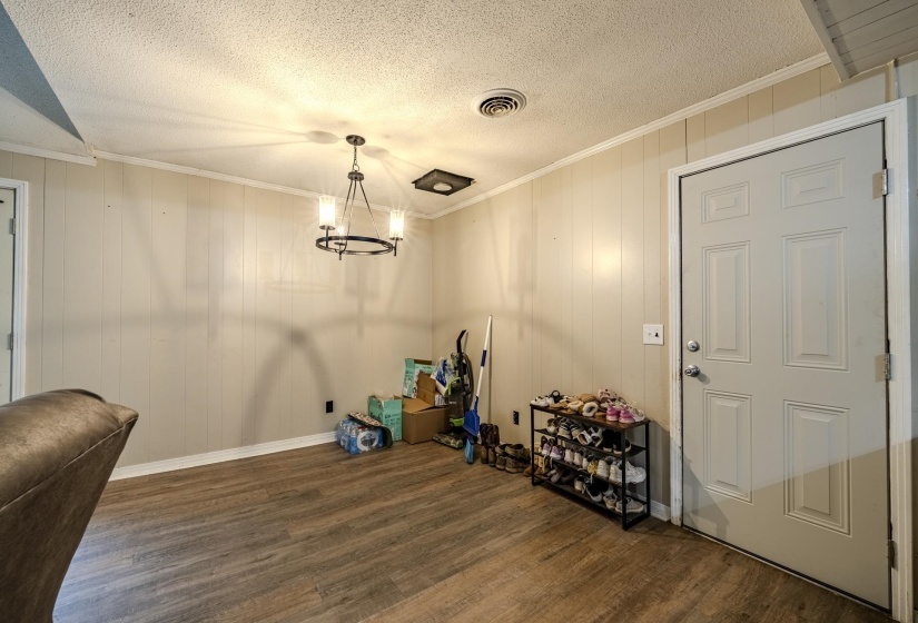 Wood-finish flooring with vertical paneling walls, crown molding, and a textured ceiling