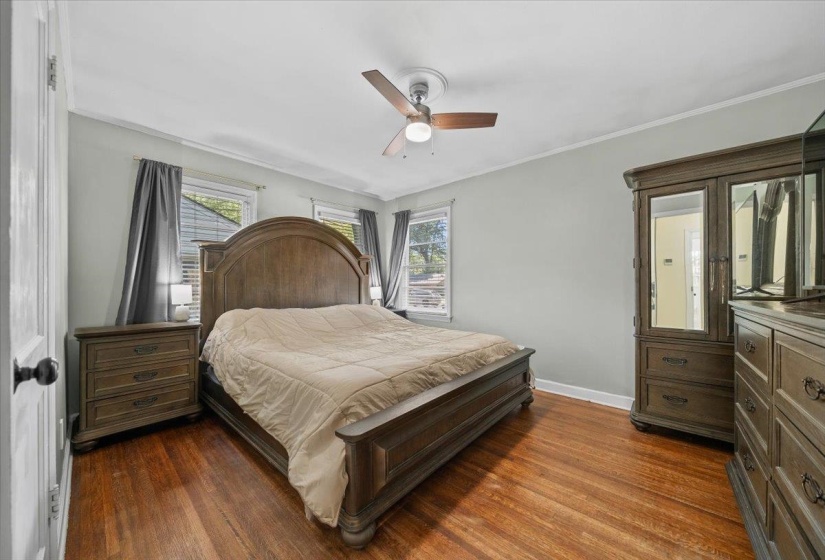 Spacious primary bedroom with real hardwood floors, ceiling fan and new paint.