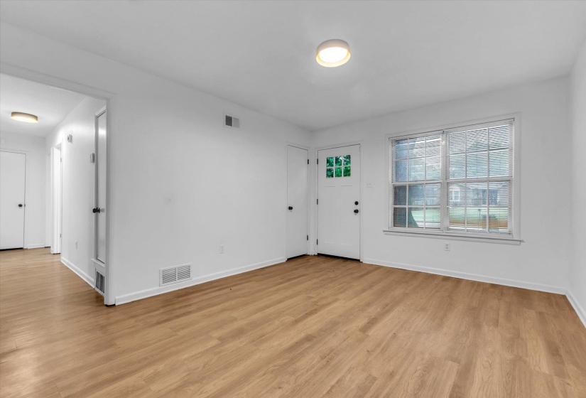 Bright living space featuring wood-finish flooring, white walls, and a front entry door with glass panels