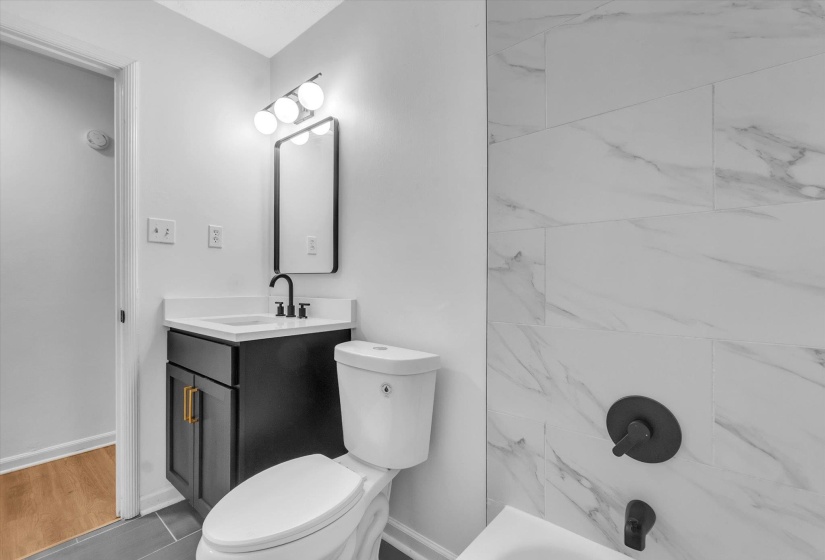 Bathroom featuring a dark wood-finish vanity with gold-tone hardware, white countertop, and integrated sink