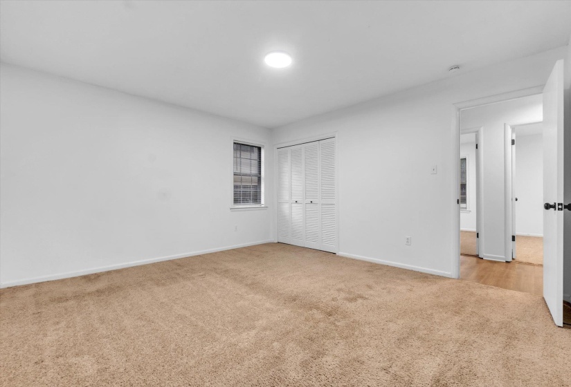 Carpeted room with white walls, a single window, and a bifold closet