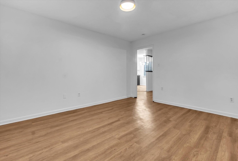 Spacious room featuring wood-finish flooring, white walls, and a ceiling-mounted light fixture