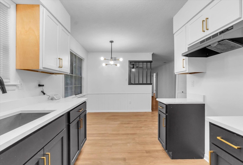 Updated kitchen featuring two-toned cabinetry with gold-tone hardware, white countertops, and a modern range hood