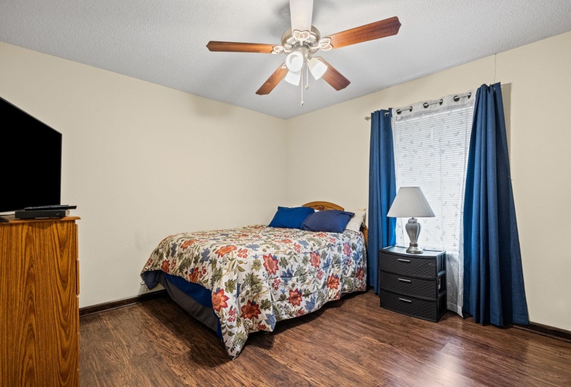 Bedroom featuring wood-finish flooring, a ceiling fan with integrated lighting, and a window with blinds