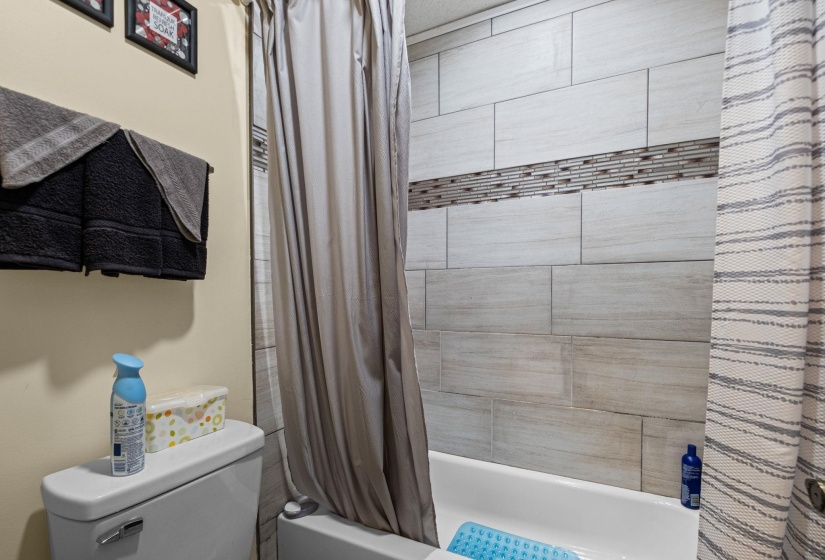 Bathtub with subway tile surround featuring a mosaic accent band