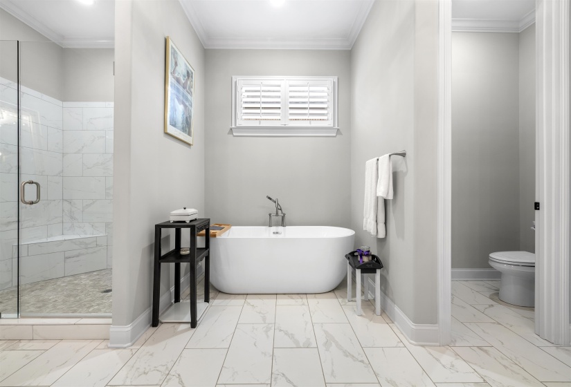 Bathroom featuring a freestanding soaking tub, a walk-in shower with glass enclosure, and white tile flooring