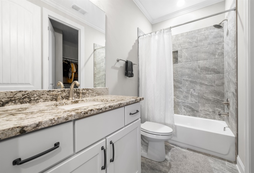 Bathroom featuring a single vanity with stone-finish countertop, undermount sink, and brushed nickel faucet