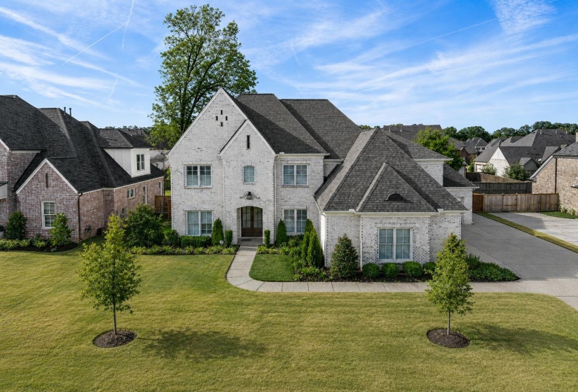 White brick facade residence featuring a front entry with an arched portico