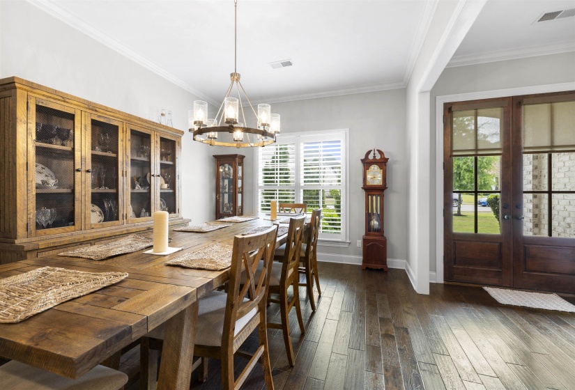 Dining area featuring wood-finish flooring, crown molding, and a chandelier with glass shades