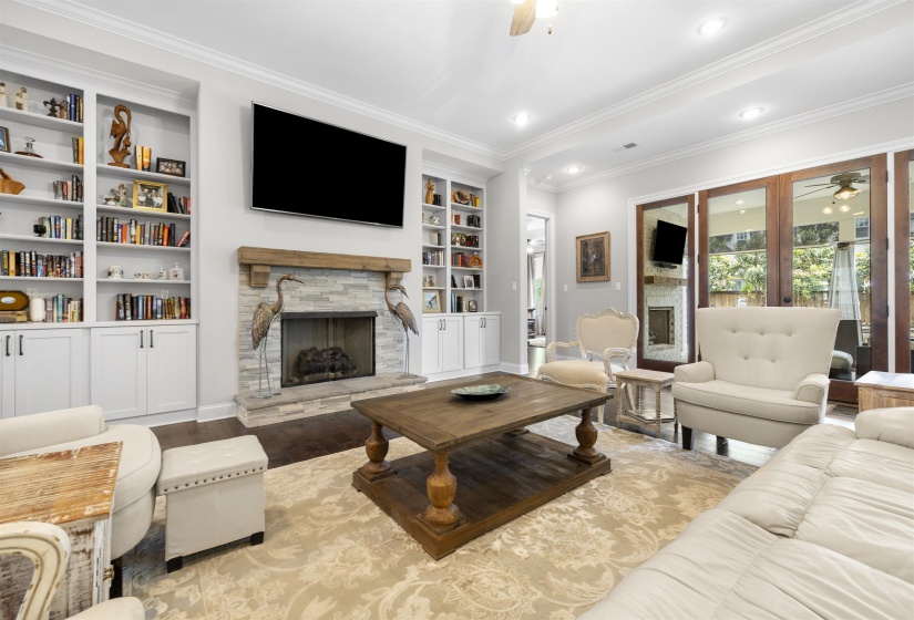 Living area featuring a stone-clad fireplace with a wood mantel, built-in shelving, recessed lighting, and wood-finish flooring