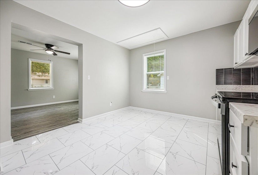 Kitchen featuring light marble finish floors, stove, healthy amount of natural light, and white cabinets
