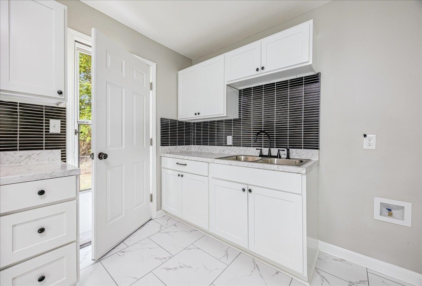 Kitchen featuring white cabinetry, light marble finish flooring, decorative backsplash, and light stone countertops