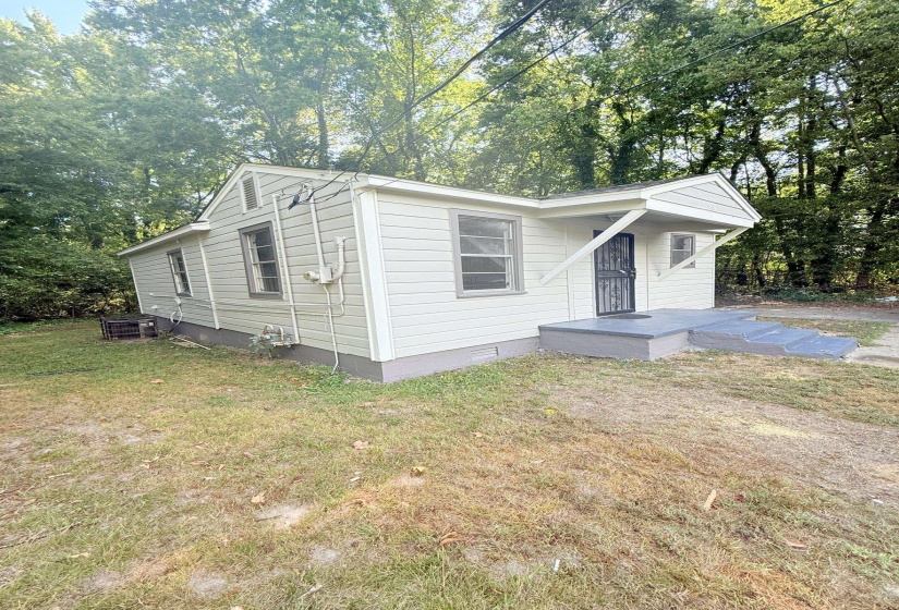 View of front of property featuring crawl space, a front lawn, and view of wooded area