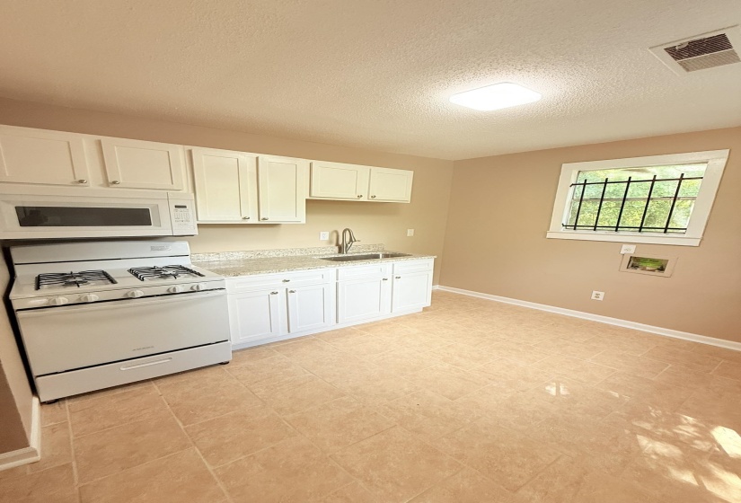 Kitchen with white appliances, white cabinets, a textured ceiling, light tile patterned flooring, and light stone countertops
