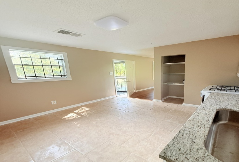 Kitchen featuring a textured ceiling, white gas range oven, light stone countertops, built in shelves, and open shelves
