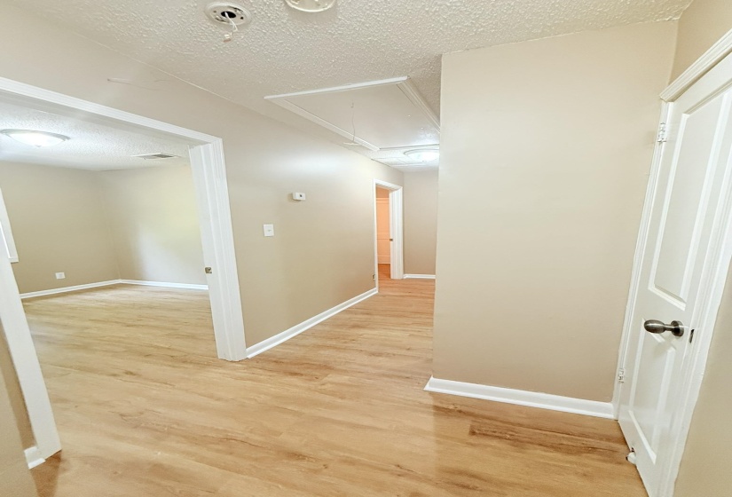 Corridor featuring a textured ceiling, attic access, and light wood-style floors