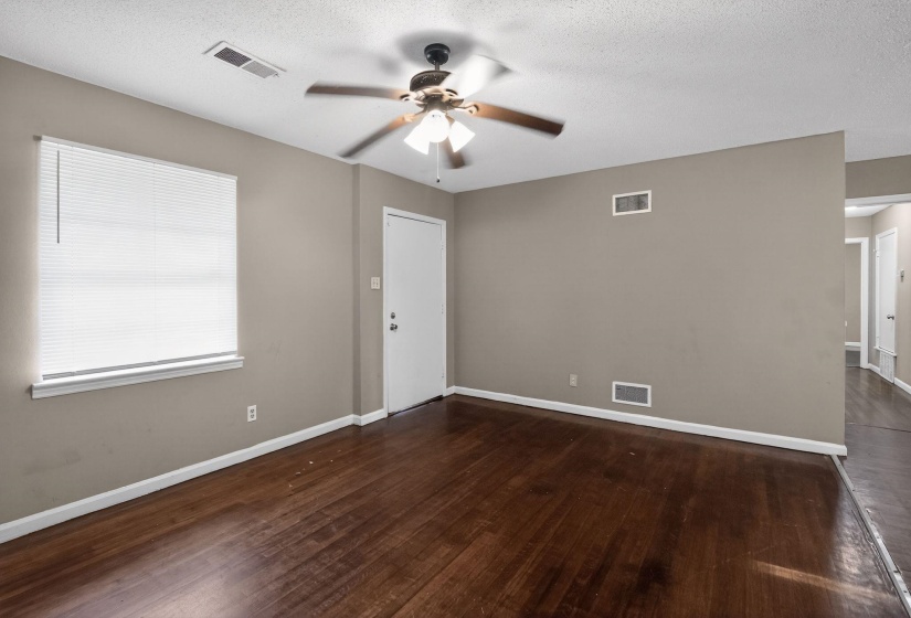 Spacious room featuring wood-finish flooring, a ceiling fan with integrated lighting, and neutral wall tones