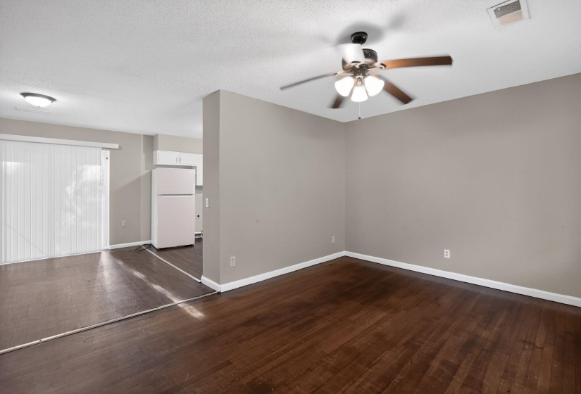 Spacious room featuring wood-finish flooring, a ceiling fan with integrated lighting, and neutral wall paint