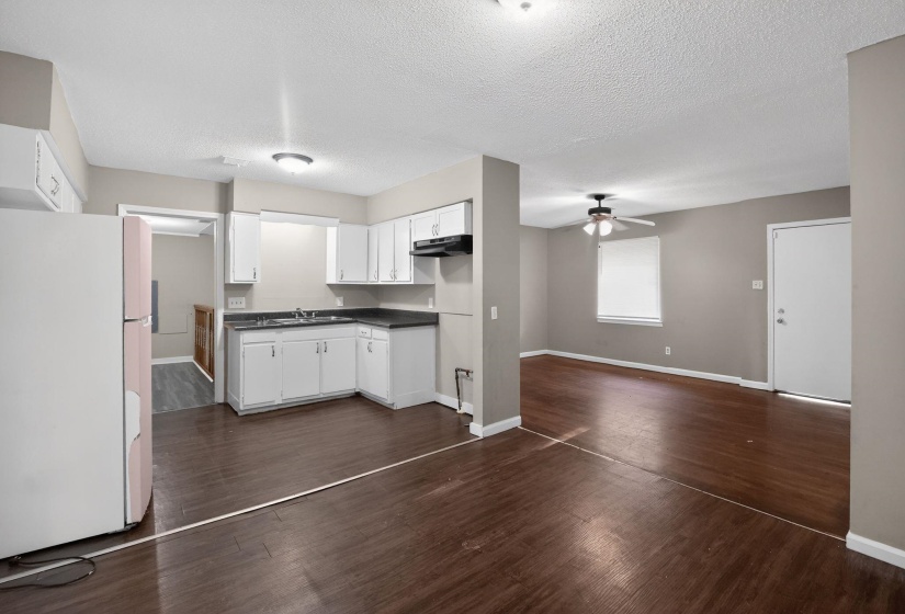 Open-concept room featuring wood-finish flooring, white cabinetry, a double basin sink, and a ceiling fan with light fixture