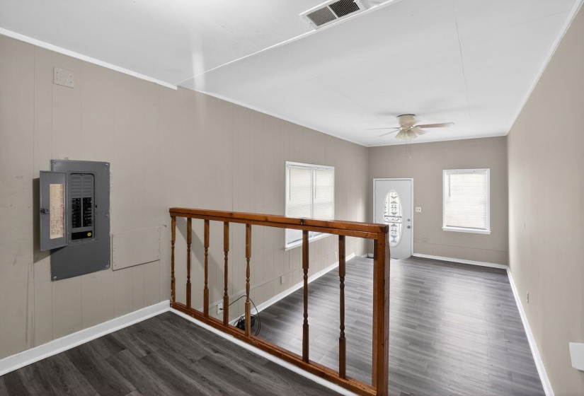 Living area featuring wood-finish flooring, a white ceiling fan, and multiple windows for natural illumination