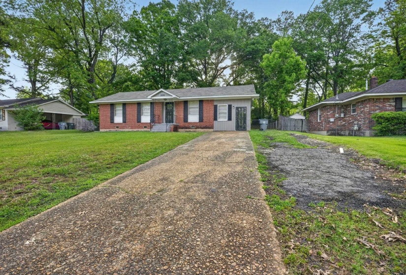 Brick exterior with white trim, front porch, and mature trees framing the property