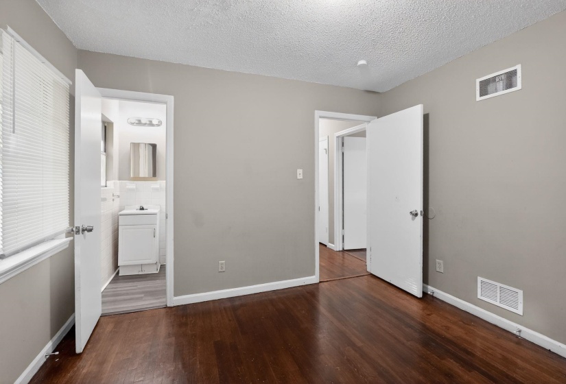 Bedroom with dark wood-finish flooring, light gray wall paint, and white trim