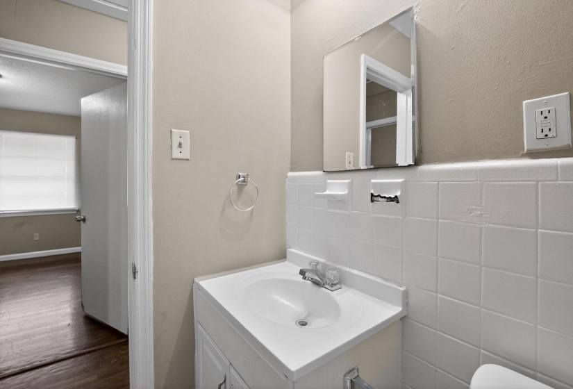 Bathroom vanity featuring a white integral sink, chrome faucet, and white base cabinetry