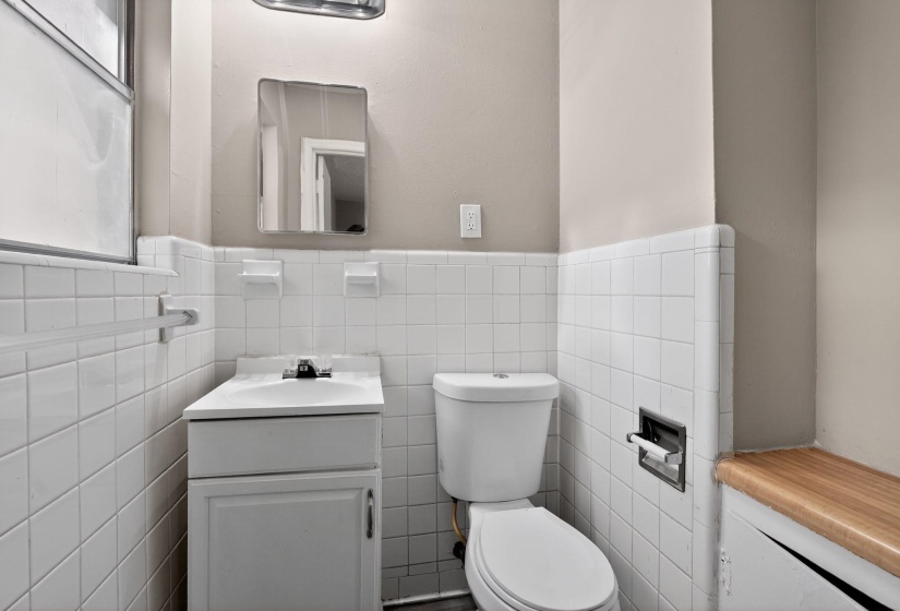 Bathroom featuring white tile wainscoting and a matching white vanity with an integrated sink