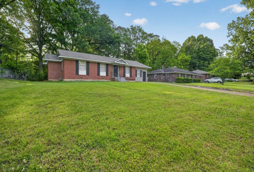 Brick exterior residence with a front lawn and mature trees