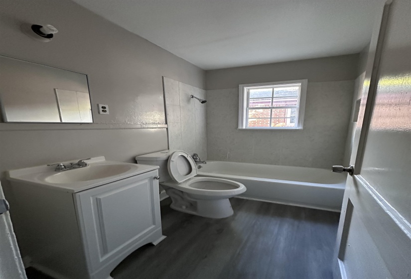 Bathroom with dark wood finished floors, bathtub / shower combination, and vanity