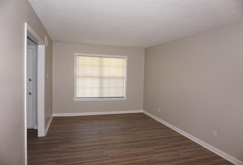 Spacious interior room featuring wood-finish flooring, neutral wall paint, and white trim