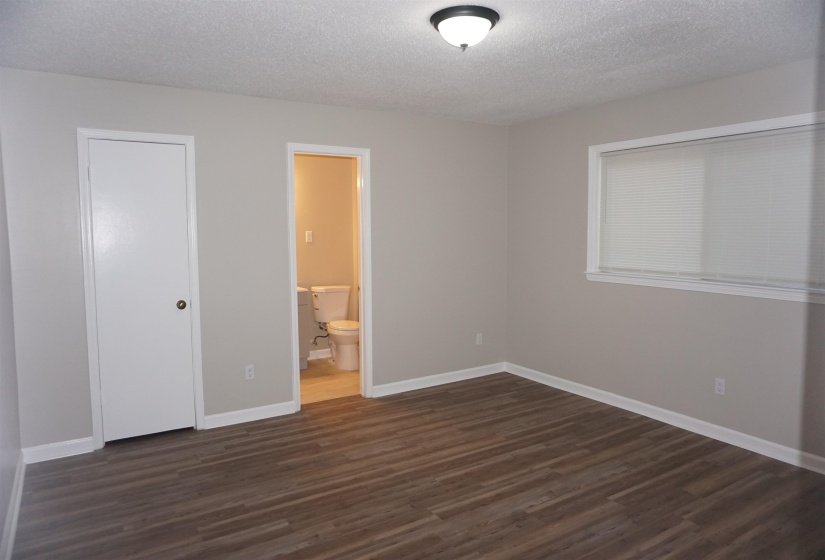 Spacious room with wood-finish flooring, neutral wall paint, and white trim