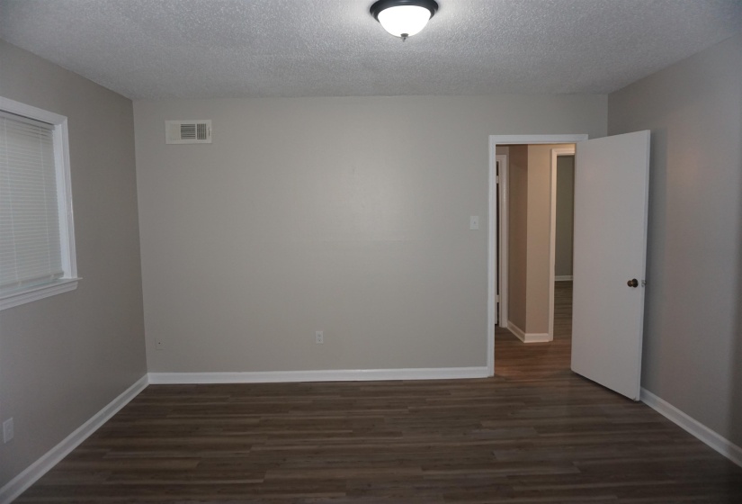 Room featuring wood-finish flooring, light gray walls, white baseboards, and a window with white blinds
