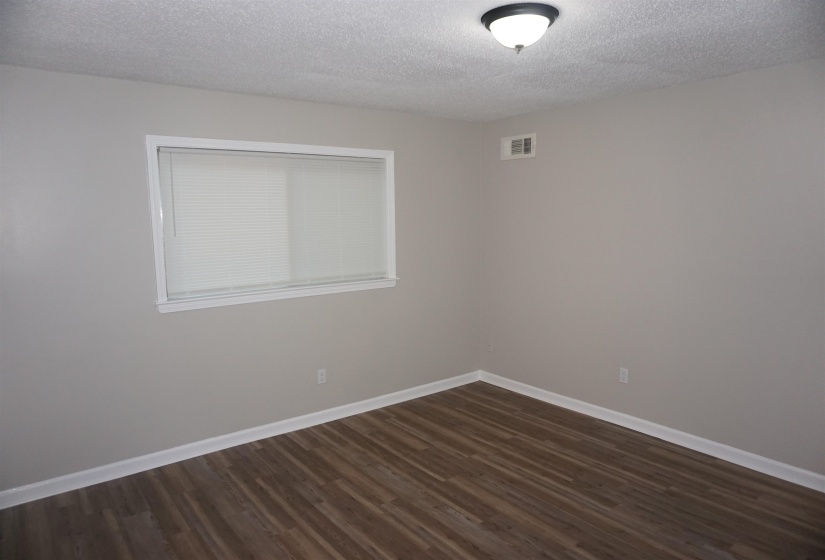 Room featuring wood-finish flooring, light gray wall paint, and white baseboards