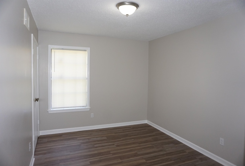 Room featuring wood-finish flooring, light gray wall paint, and white trim