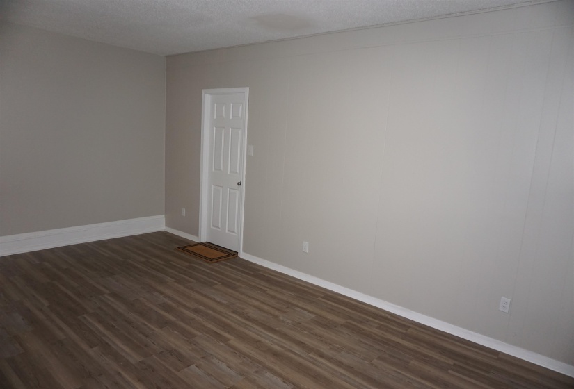 Spacious room featuring wood-finish flooring, light neutral wall paint, and white baseboards