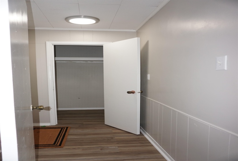 Hallway featuring wood-finish flooring and wainscoting