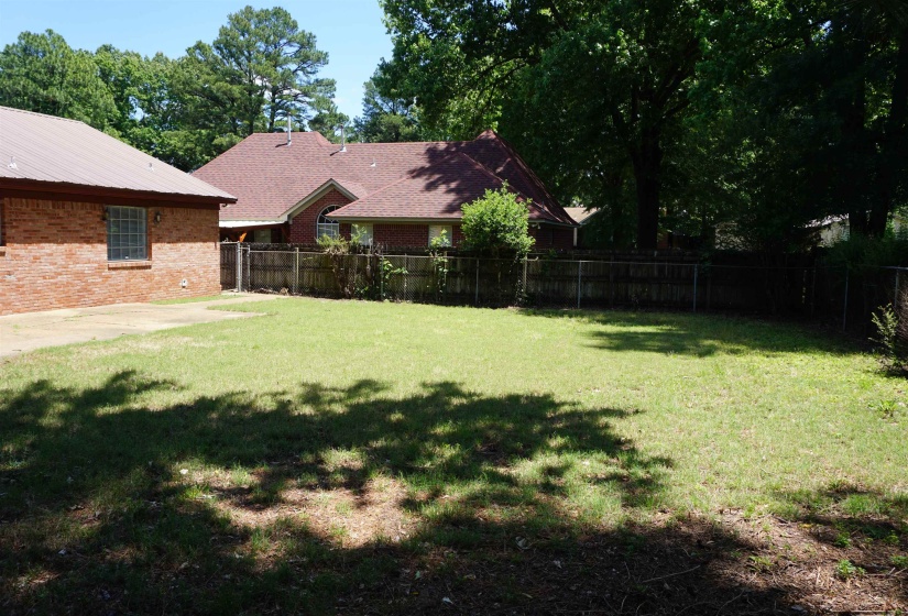 Expansive grassy yard with mature trees and a chain-link fence bordering the property