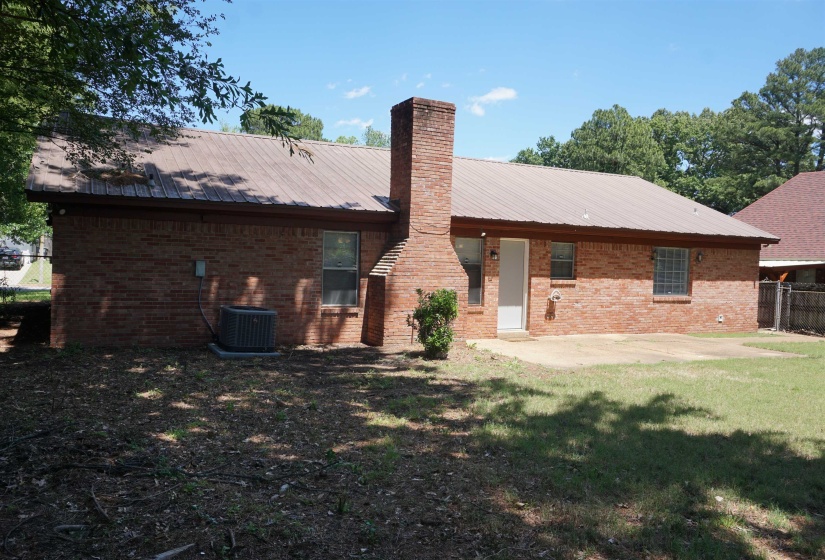 Brick exterior residence featuring a metal roof and a prominent brick chimney