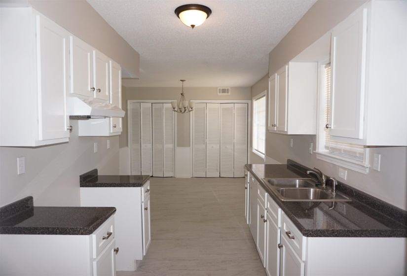 Galley-style kitchen featuring white cabinetry, dark speckled countertops, and a dual basin stainless steel sink
