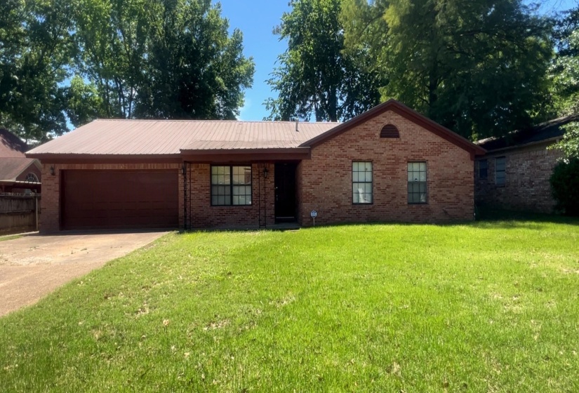 Brick exterior with a peaked roofline, front-facing garage, and a lush green lawn